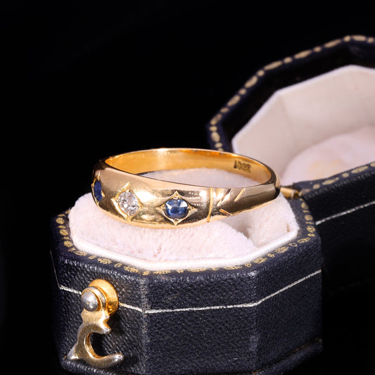 Three-stone gypsy-set ring with central diamond flanked by two blue sapphires