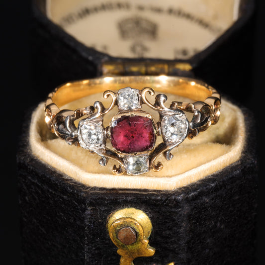 Georgian garnet and diamond filigree ring in high-carat yellow gold with scrolling wirework shoulders and a central flat-cut garnet surrounded by old cut diamonds