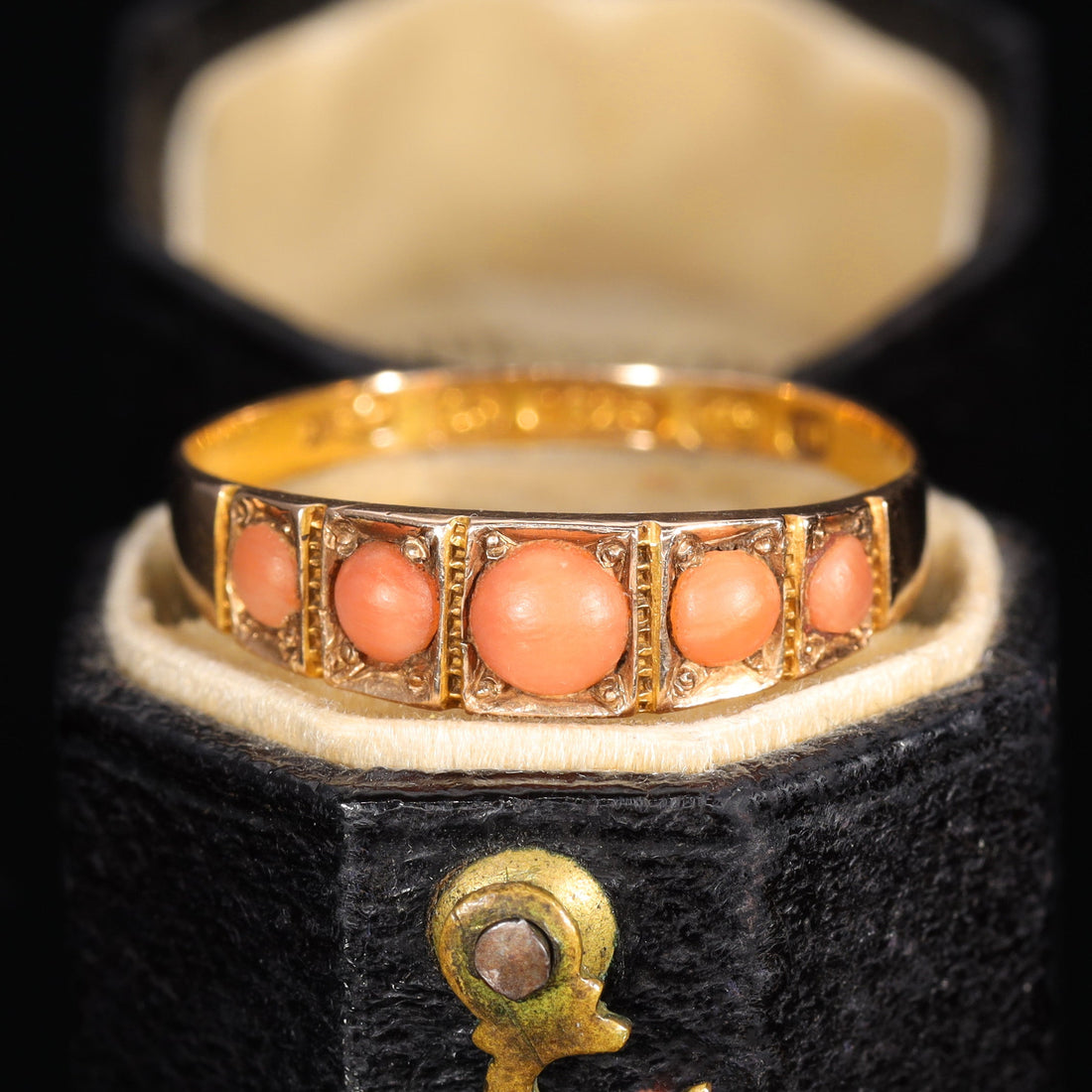 Victorian five stone coral ring in yellow gold, circa 1900, with five graduated salmon-pink coral cabochons in individual collet settings with beaded metalwork