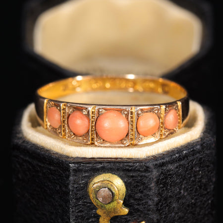Victorian five stone coral ring in yellow gold, circa 1900, with five graduated salmon-pink coral cabochons in individual collet settings with beaded metalwork