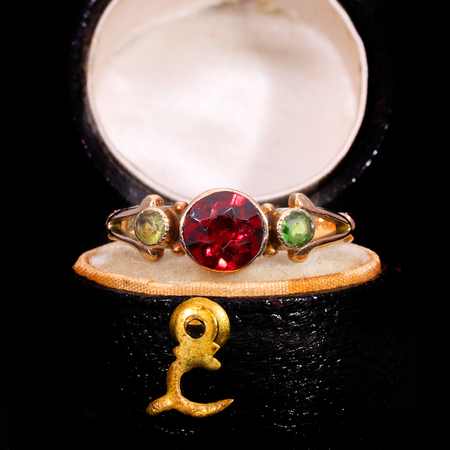 Edwardian three stone ring in gold with central red garnet flanked by two green peridots, circa 1911