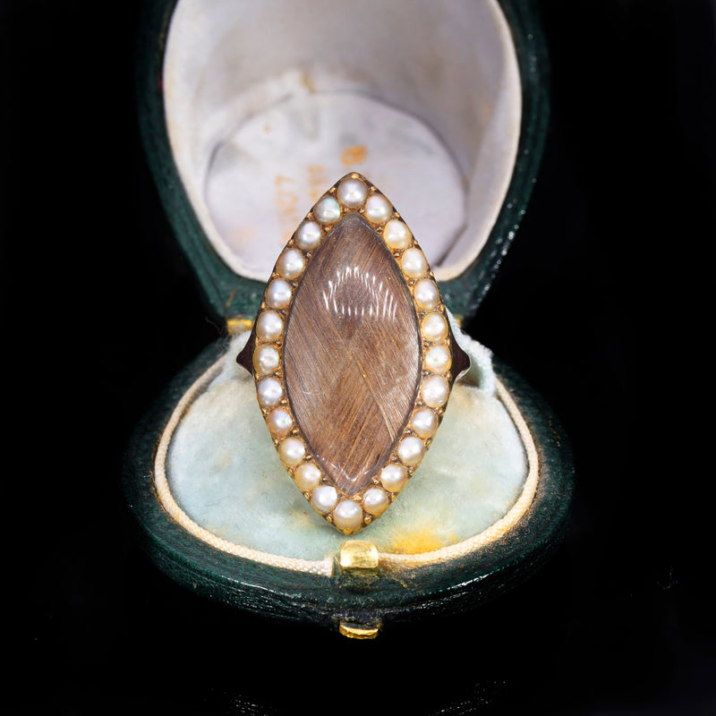 Early Victorian hairwork mourning ring in navette form with woven hair preserved beneath glass and framed by seed pearls