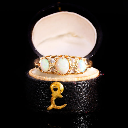 Victorian three-opal and diamond ring in 18ct yellow gold, circa 1898, with three graduated cabochon opals displaying play of colour separated by pairs of old cut diamonds