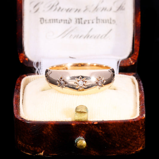Vintage 1953 gold band ring with three brilliant cut diamonds in star settings, displayed in original antique jeweller's box