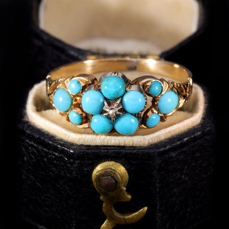 Victorian turquoise forget-me-not mourning ring in yellow gold with turquoise cabochons arranged in a floral cluster around a central diamond, with additional turquoise stones on the shoulders