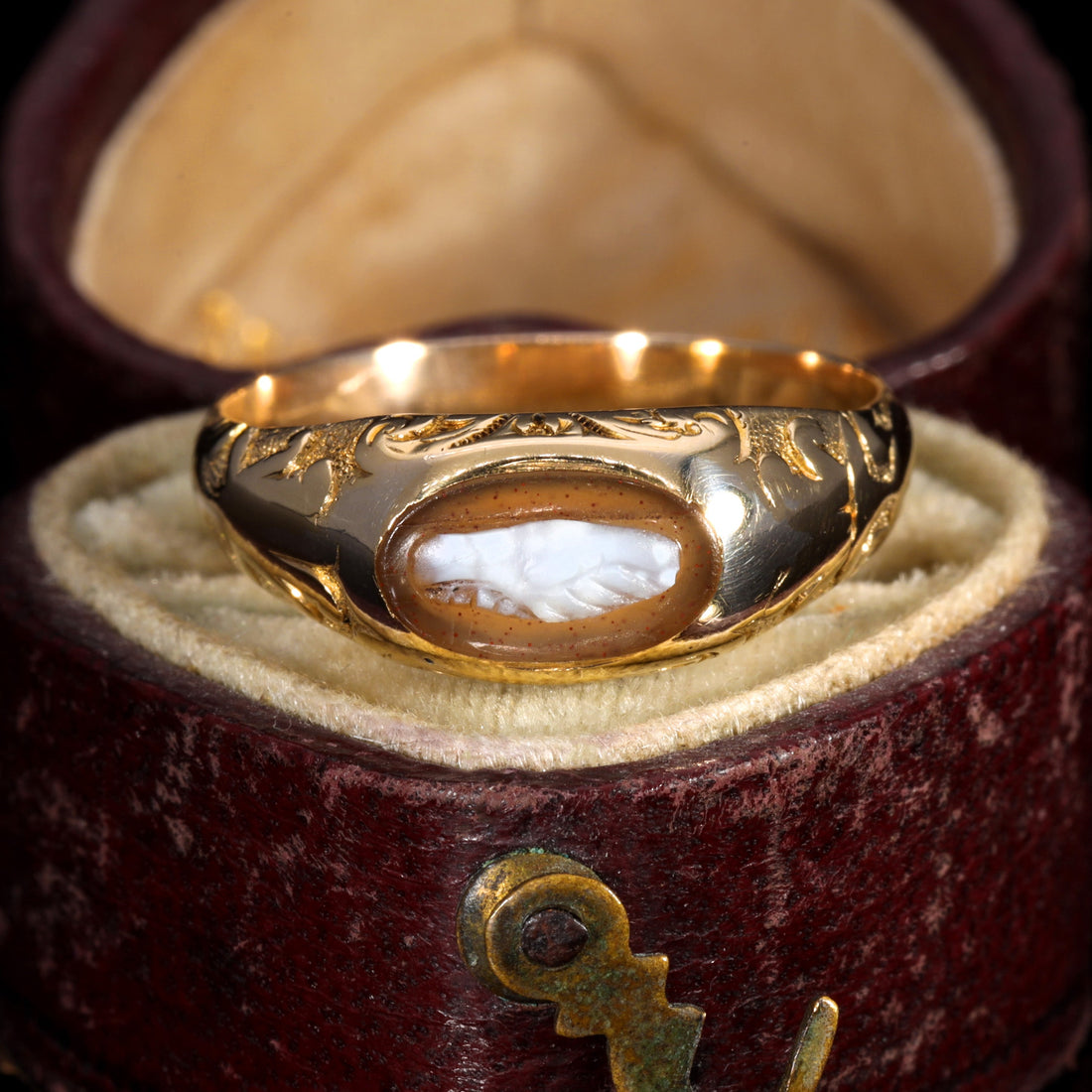 Victorian fede ring in gold with a two-toned agate cameo depicting clasped hands, set into an engraved band with foliate shoulders, displayed in an antique ring box
