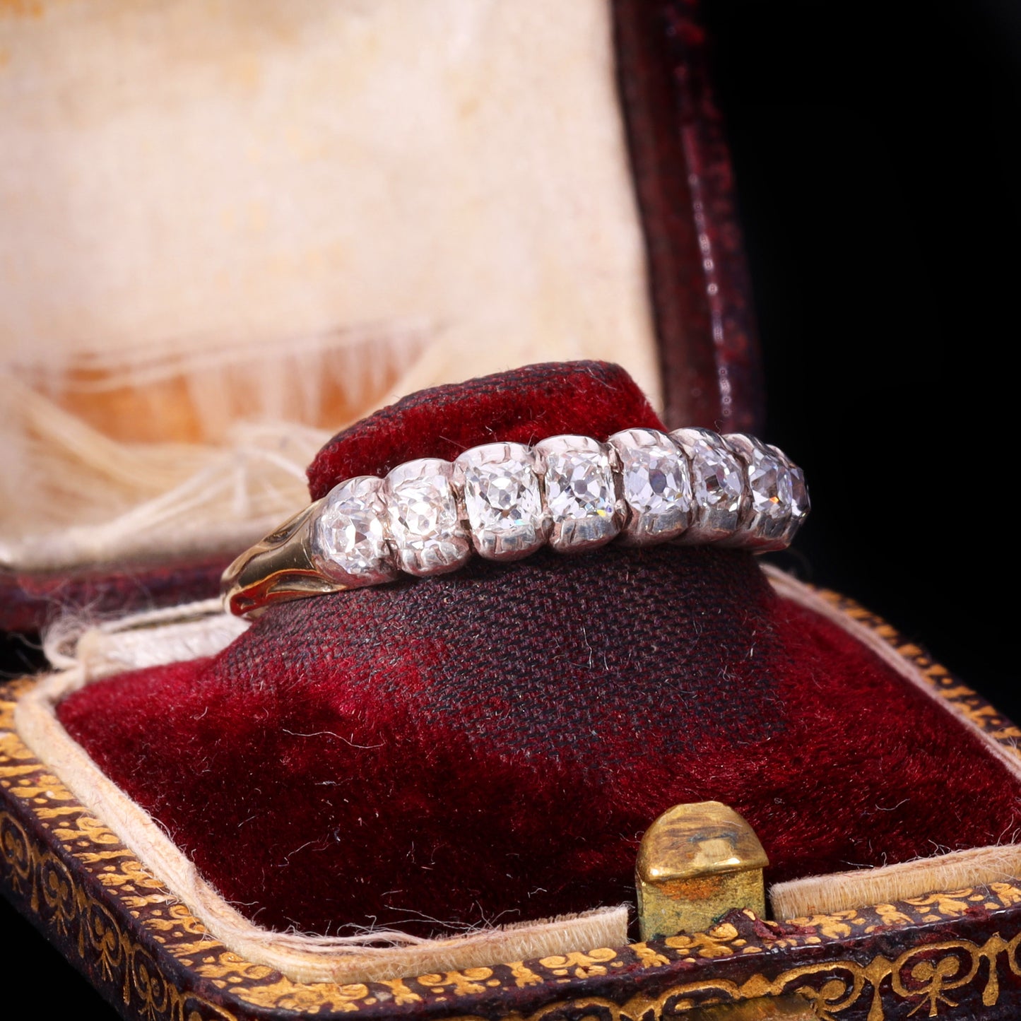 Side profile of eight graduated old mine-cut diamonds in silver grain-and-claw settings