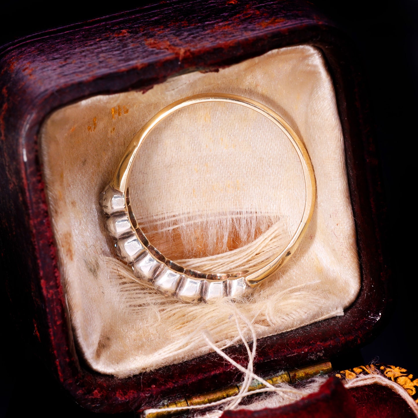 Side profile showing silver grain-and-claw set old mine-cut diamond half hoop