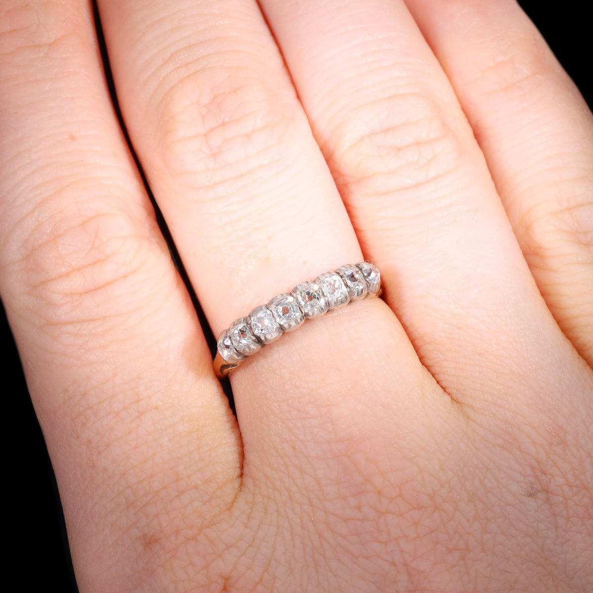 Ring worn on hand showing scale of eight-stone old mine-cut diamond half hoop band