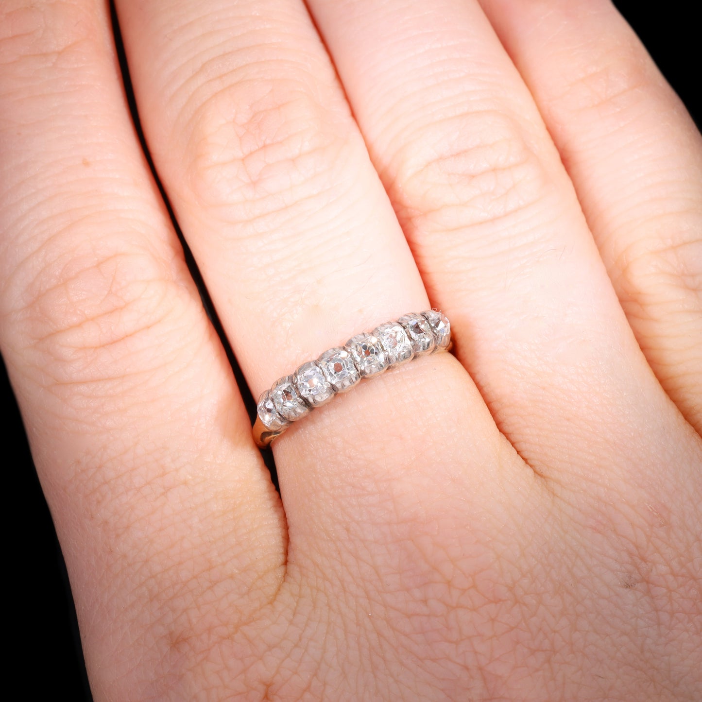 Ring worn on hand showing scale of eight-stone old mine-cut diamond half hoop band