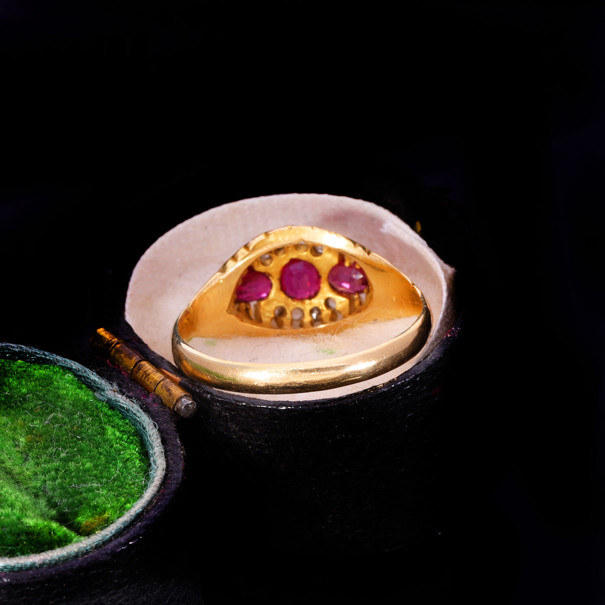 Underside view showing open claw settings and three oval rubies in 18ct gold mount