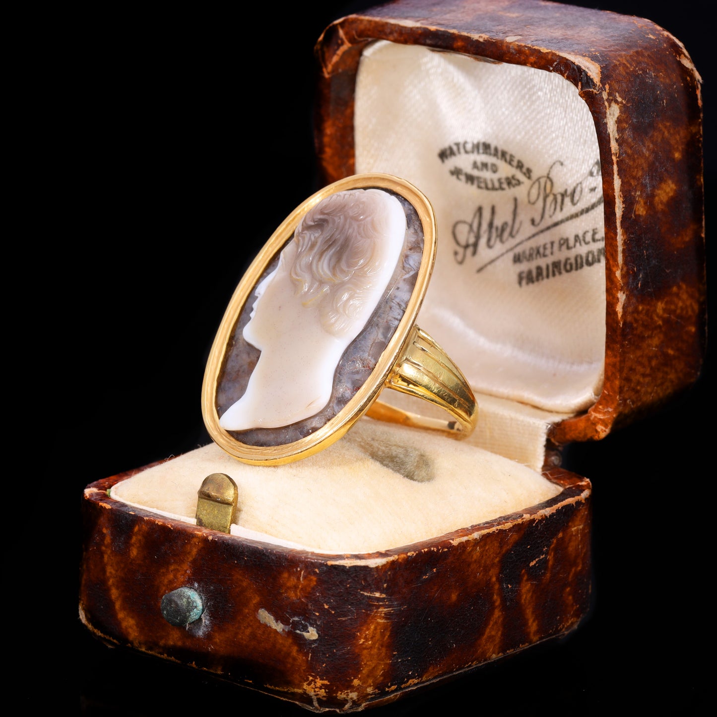 Three-quarter view of sardonyx cameo ring showing male profile carving in yellow gold setting