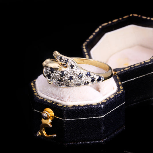 Three-quarter view of sapphire and diamond panther ring showing studded body and open-mouthed head