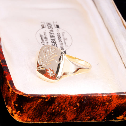 Three-quarter view of 9ct gold signet ring with fleur-de-lis engraving and star-set diamond