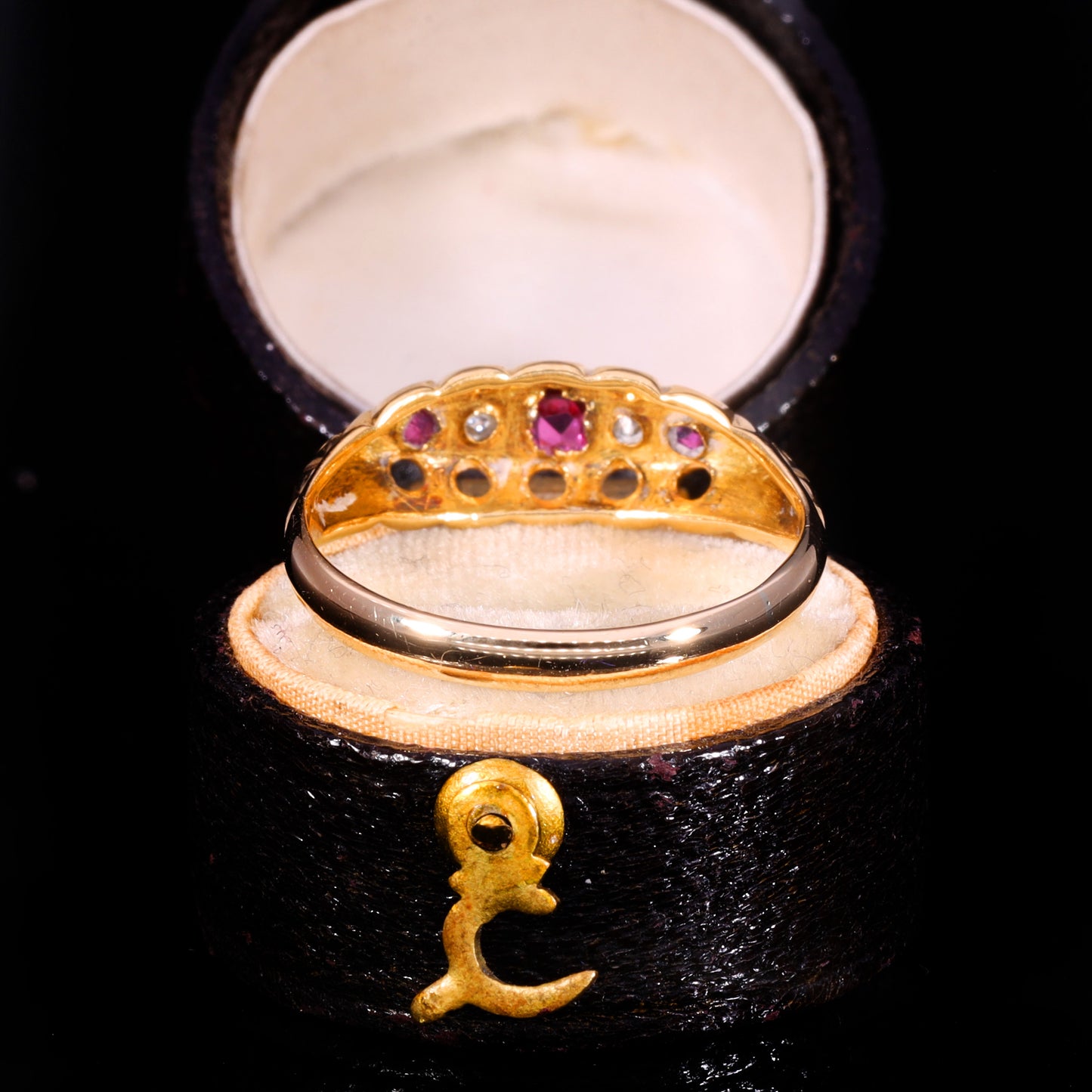 Underside view showing open gallery with circular cut-outs and ruby and diamond settings