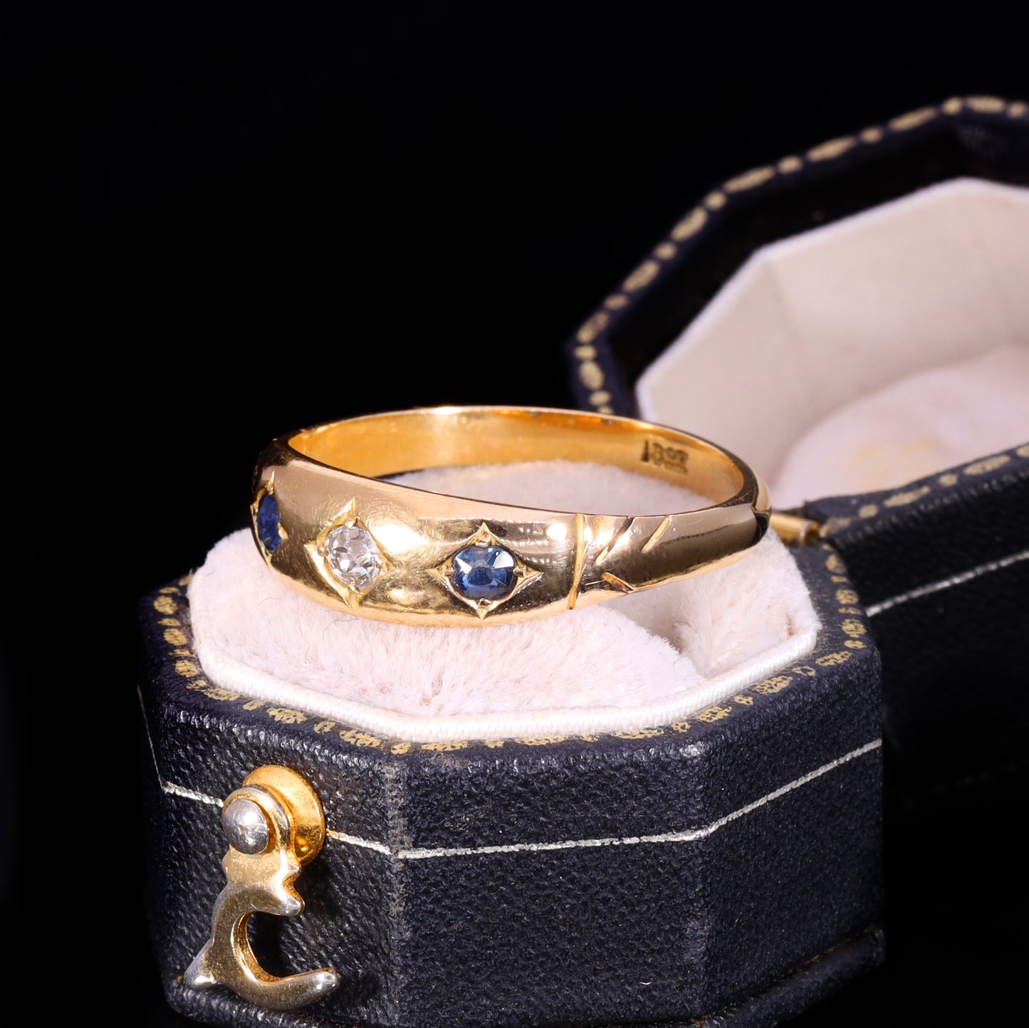 Three-stone gypsy-set ring with central diamond flanked by two blue sapphires