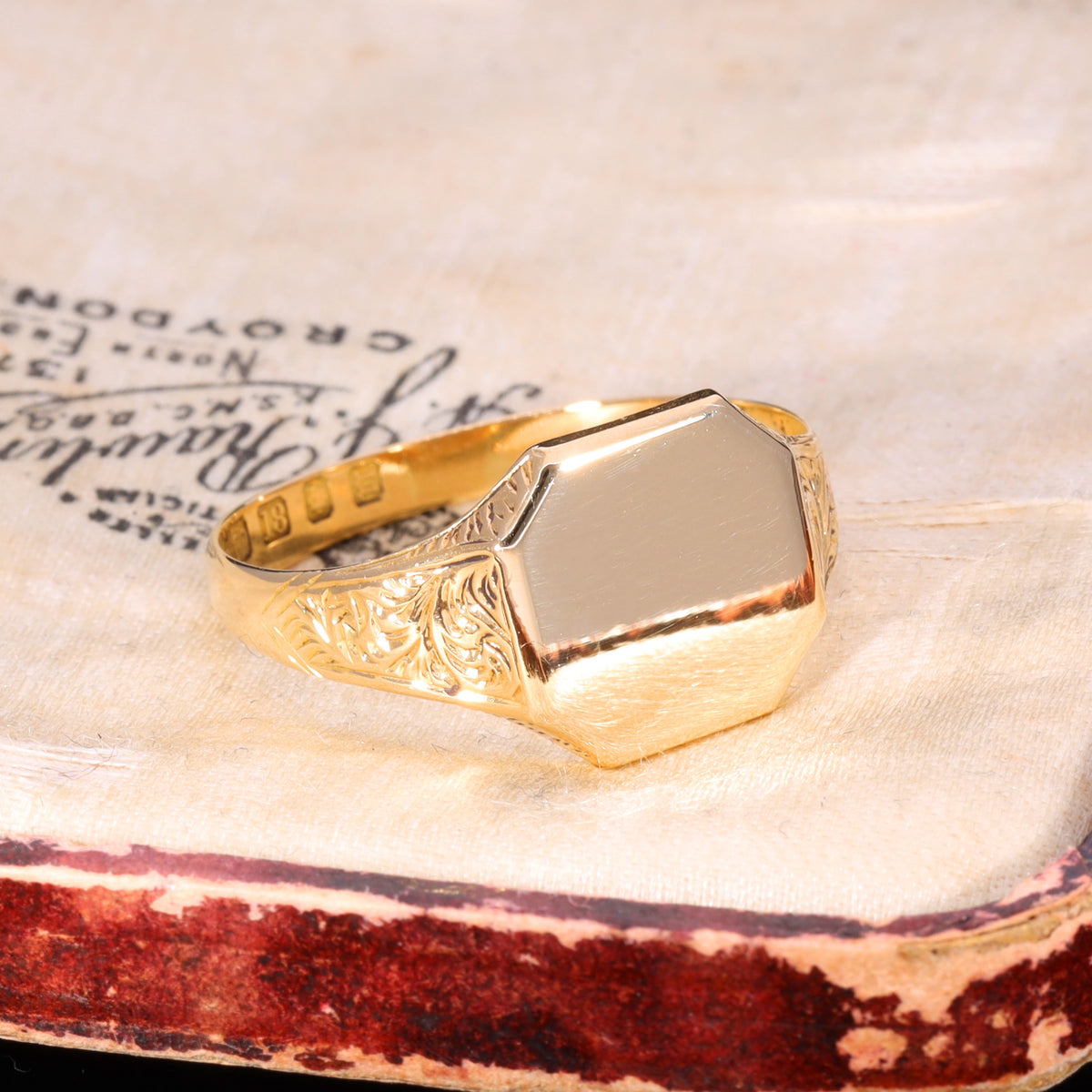 Three-quarter view of Victorian 18ct gold signet ring with foliolate shoulder engraving