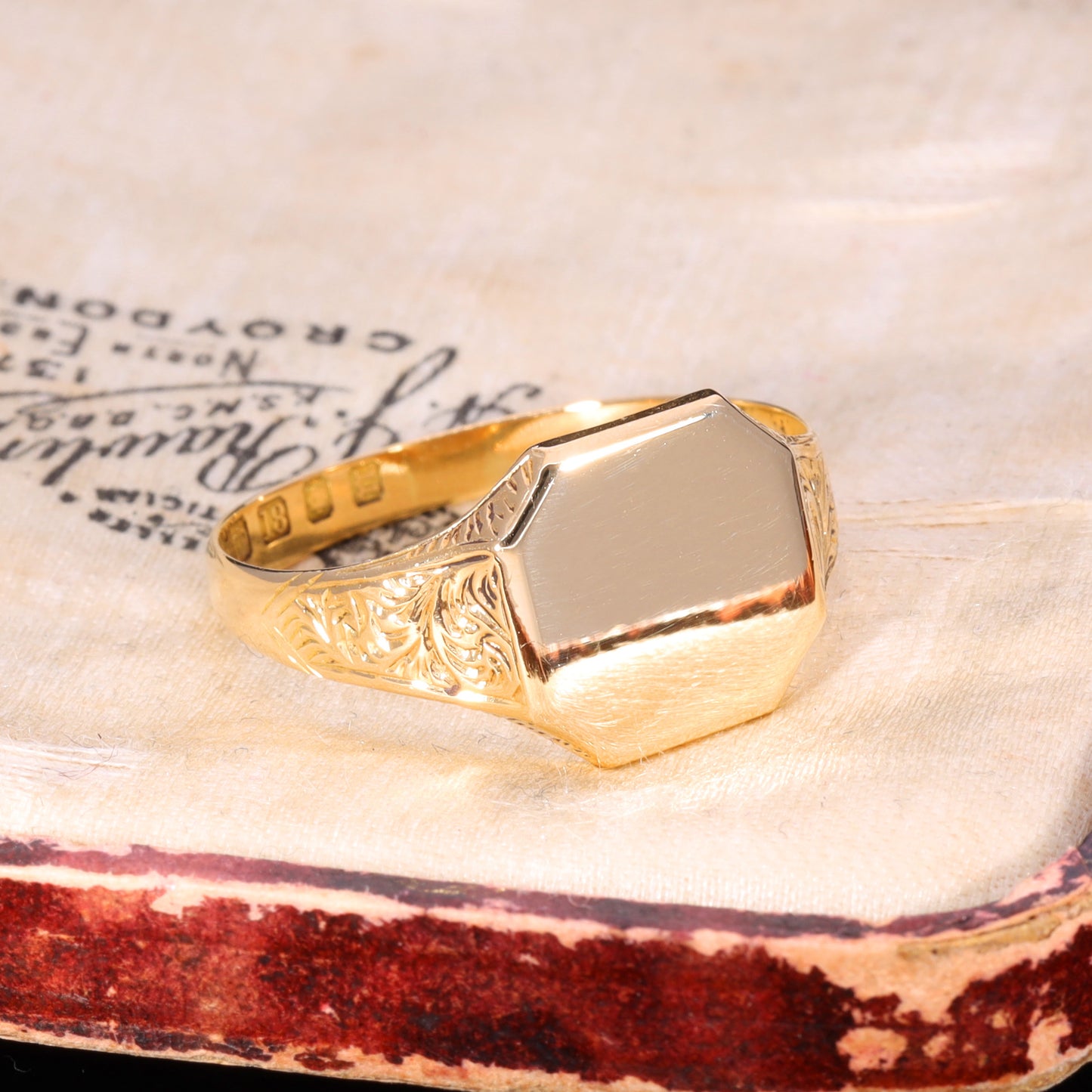 Three-quarter view of Victorian 18ct gold signet ring with foliolate shoulder engraving